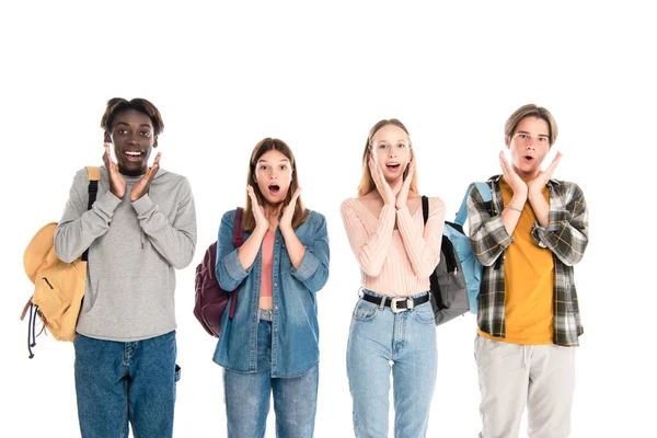 Adolescentes multiétnicos chocados com mochilas olhando para a câmera isolada no branco — Fotografia de Stock