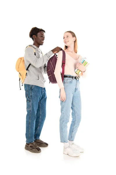 Улыбающийся африканский американец в рюкзаке на друге с книгами на белом фоне — стоковое фото