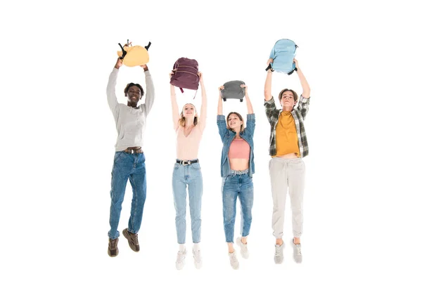 Adolescentes multiculturais positivos pulando com mochilas isoladas em branco — Fotografia de Stock