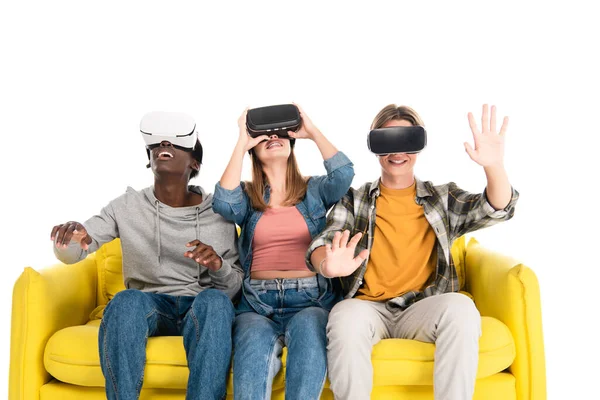 Adolescentes multiétnicos alegres usando fones de ouvido vr no sofá amarelo isolado no branco — Fotografia de Stock