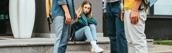 Horizontal crop of sad girl looking at multiethnic teenagers outdoors — Stock Photo