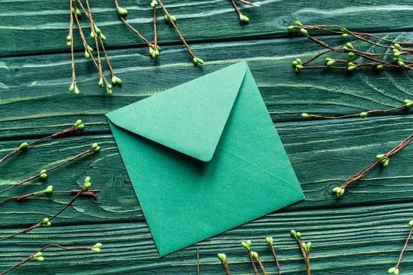 Vue de dessus du fond vert en bois avec des branches florissantes et enveloppe — Photo de stock