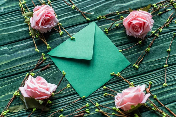 Wooden green background with blossoming branches, roses and envelope — Stock Photo