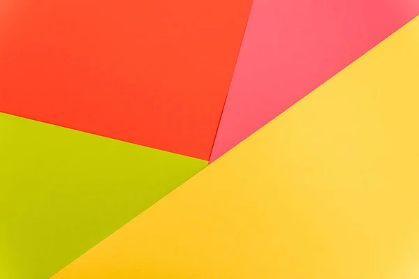 Вид зверху барвистий абстрактний жовтий, червоний, зелений і рожевий паперовий фон — стокове фото