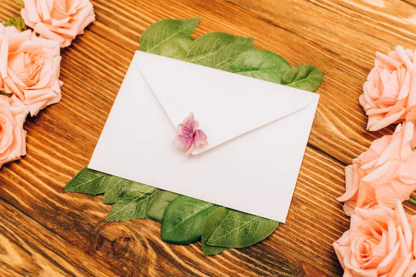 Draufsicht auf Briefumschlag in der Nähe von Rosen auf Holzgrund — Stockfoto