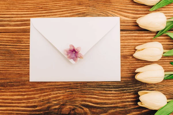 Top view of envelope near tulips on wooden background — Stock Photo