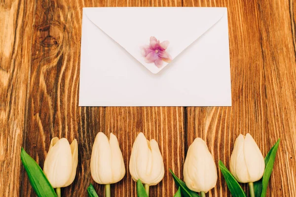 Vue de dessus de l'enveloppe près des tulipes sur fond en bois — Photo de stock