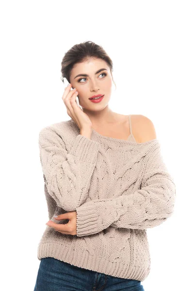 Dreamy woman in trendy sweater talking on smartphone and looking away isolated on white — Stock Photo