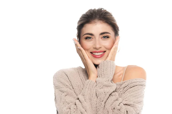 Femme joyeuse en chandail ajouré toucher le visage tout en regardant la caméra isolée sur blanc — Photo de stock