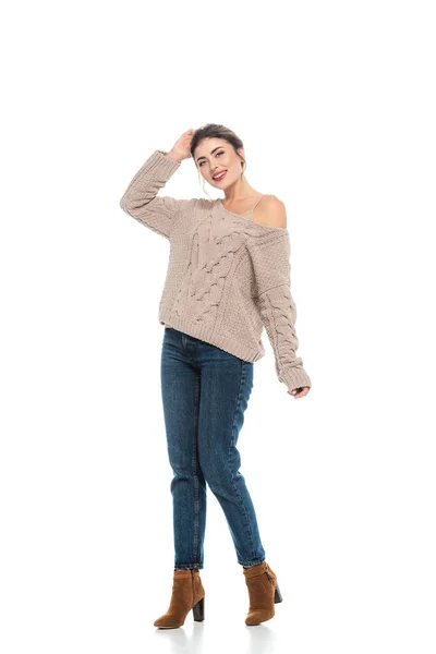 Повнометражний вигляд стильної жінки в трикотажному светрі і джинсах позує на білому — стокове фото