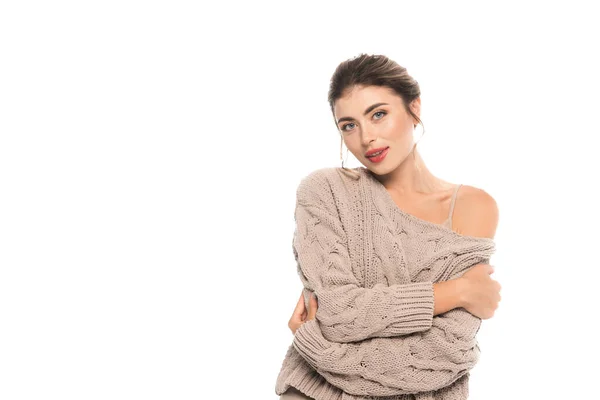 Trendfrau im durchbrochenen Pullover blickt in die Kamera, während sie sich isoliert auf weiß umarmt — Stockfoto