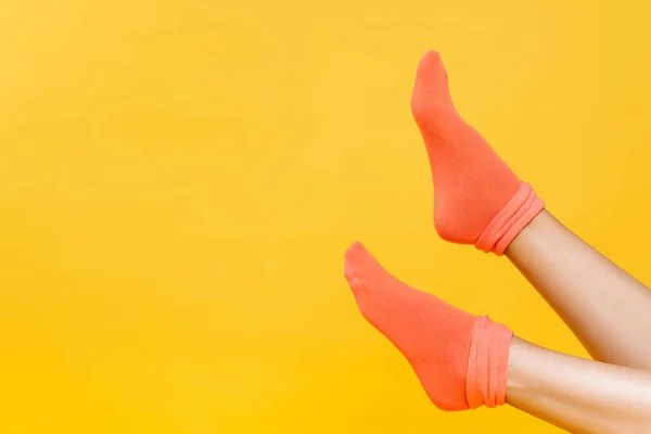 Vista recortada de las piernas femeninas en calcetines anaranjados suaves aislados en amarillo - foto de stock