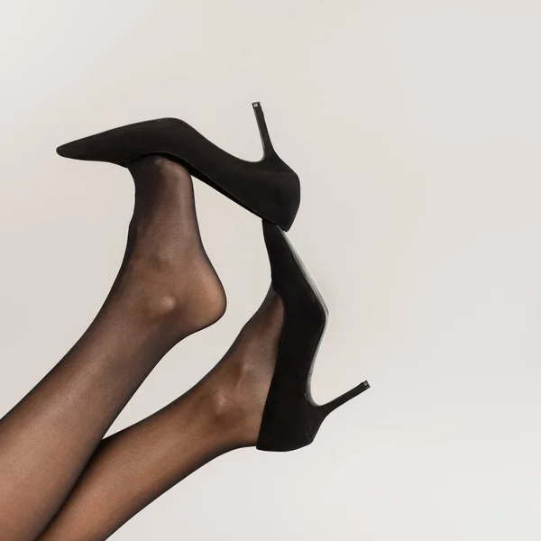 Cropped view of woman with legs in air, wearing black tights and shoes with heels isolated on grey — Stock Photo