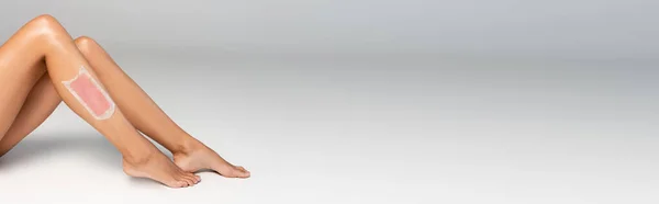 Donna gambe lisce con striscia di cera rosa su grigio, banner — Foto stock
