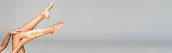 Femme avec les jambes dans l'air appliquant une bande de cire sur le gris, bannière — Photo de stock