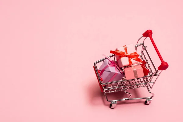 Visão de alto ângulo do carrinho de compras de brinquedos com presentes no conceito rosa, preto sexta-feira — Fotografia de Stock