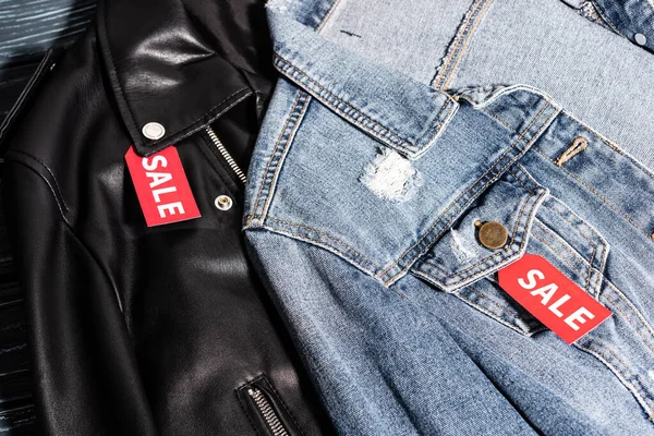 Close up of denim and leather jackets with sale tags, black friday concept — Stock Photo