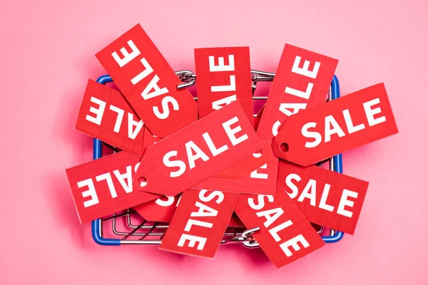Vista superior de etiquetas con letras de venta en cesta de la compra en rosa, concepto de viernes negro - foto de stock