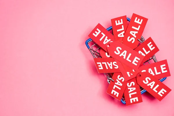 Vista superior de etiquetas de venda na cesta de compras no rosa, conceito de sexta-feira preta — Fotografia de Stock