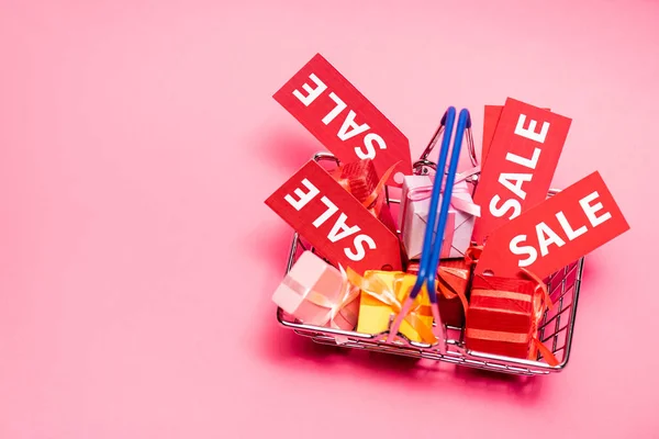 Vue du haut du panier avec des cadeaux et des étiquettes de vente sur rose — Photo de stock