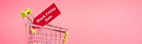 Horizontal concept of red tag with black friday sale lettering in shopping cart isolated on pink — Stock Photo