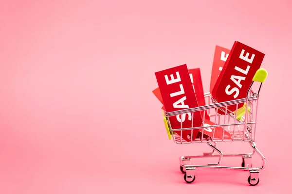 Etiquetas vermelhas com lettering venda sexta-feira preta no carrinho de compras em rosa — Fotografia de Stock