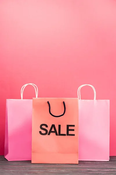 Bolsa de compras con letras de la venta cerca de paquetes de papel en rosa, concepto de viernes negro - foto de stock