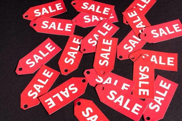 Top view of red labels with sale lettering on black background — Stock Photo
