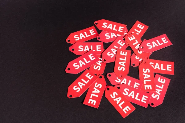 Red labels with sale lettering on black background with copy space — Stock Photo