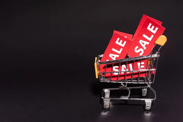 Toy cart with sale tags on dark background, black friday concept — Stock Photo