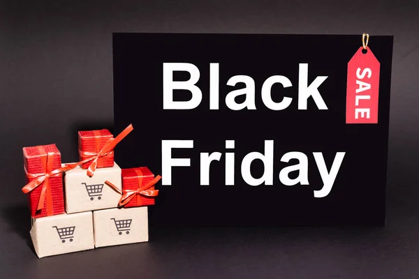 Geschenke in der Nähe von kleinen Kartons in der Nähe von Plakaten mit schwarzem Freitag Schriftzug auf dunklem Hintergrund — Stockfoto