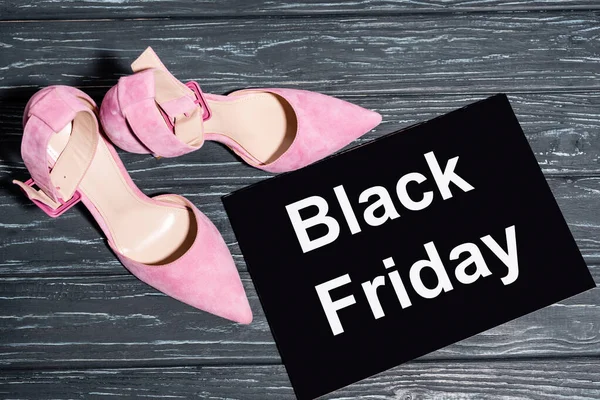 Draufsicht auf rosa Schuhe in der Nähe von Plakat mit schwarzem Freitag Schriftzug auf Holzoberfläche — Stockfoto
