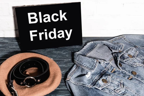 Denim jacket near placard with black friday lettering, beret and belt — Stock Photo