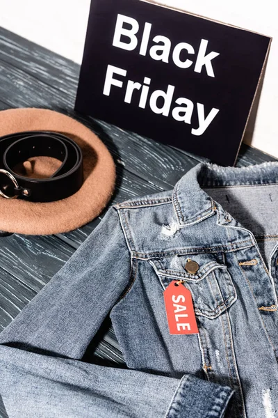Blaue Jeansjacke neben Plakat mit schwarzem Freitag Schriftzug, Baskenmütze und Gürtel — Stockfoto
