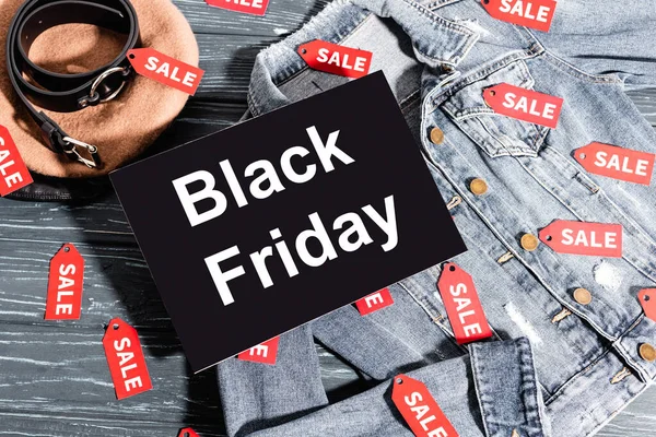 Top view of placard with black friday lettering on denim jacket near beret and belt — Stock Photo