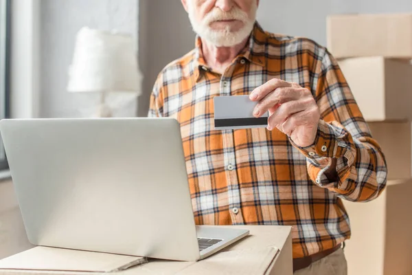 Partial view of senior man making online purchase with credit card and laptop — Stock Photo