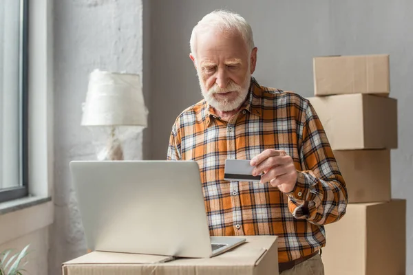 Старший человек делает онлайн покупку с помощью кредитной карты и ноутбука — стоковое фото
