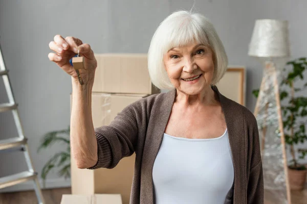 Sonriente mujer mayor sosteniendo llaves, concepto en movimiento - foto de stock