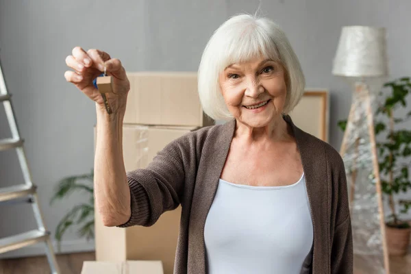 Sorridente mulher sênior segurando chaves, conceito em movimento — Fotografia de Stock