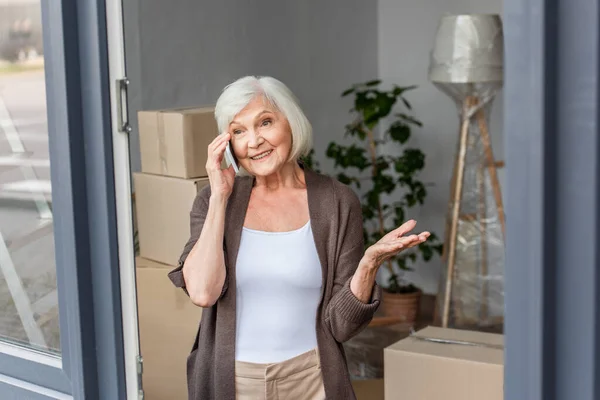 Felice donna anziana parlando al telefono in una nuova casa, concetto in movimento — Foto stock