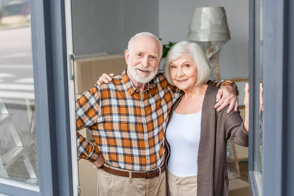 Cheerful senior couple embracing each other in new house — Stock Photo