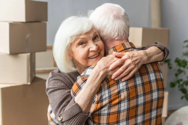 Senior woman hugging husband in new house, moving concept — Stock Photo
