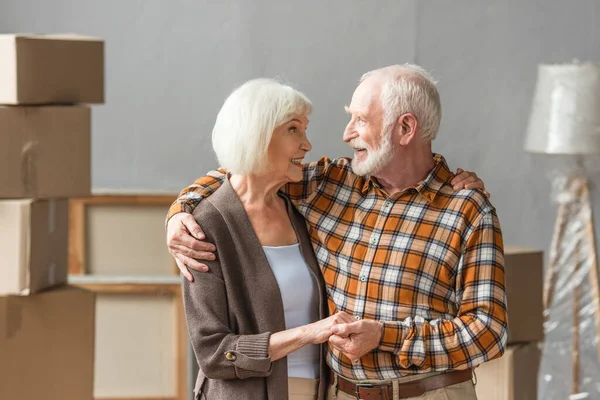 Пожилая пара, обнимающая и держащаяся за руки в новом доме, движущаяся концепция — стоковое фото