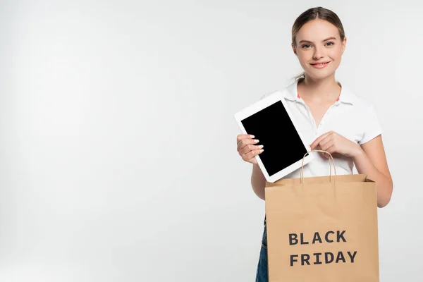 Jovem segurando tablet digital com tela em branco e saco de compras com letras sexta-feira preto isolado no branco — Fotografia de Stock