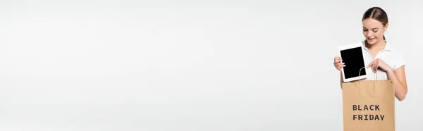Cabeçalho do site de mulher jovem apontando com o dedo para tablet digital com tela em branco perto de saco de compras com letras sexta-feira preto isolado em branco — Fotografia de Stock
