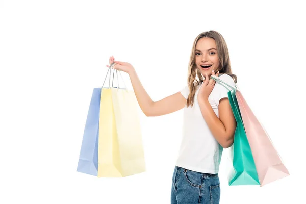 Junge aufgeregte Frau hält bunte Einkaufstüten in der Hand und blickt vereinzelt in die Kamera — Stockfoto