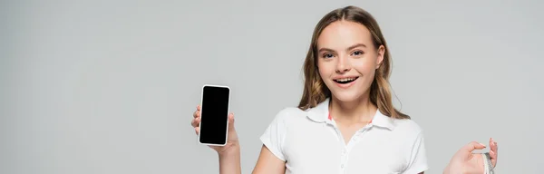 Colheita panorâmica de mulher alegre segurando smartphone com tela em branco isolado em cinza — Fotografia de Stock