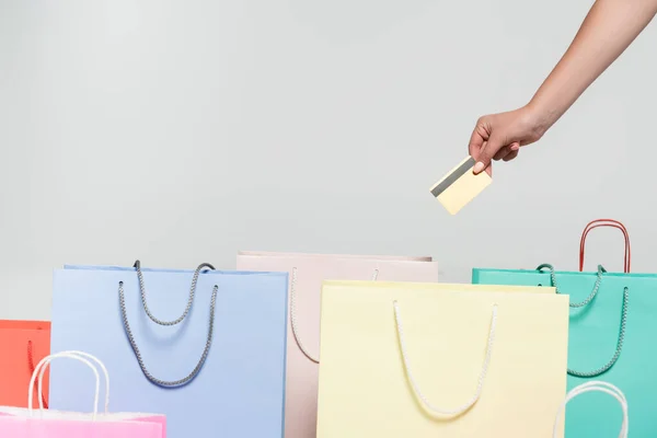 Vista cortada da mulher segurando cartão de crédito perto de sacos de compras isolados no conceito cinza, preto sexta-feira — Fotografia de Stock