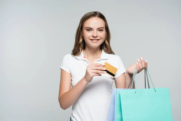 Joyful young woman holding credit card and shopping bags isolated on grey, black friday concept — Stock Photo