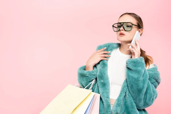 Mulher na moda em óculos de sol falando no smartphone e segurando sacos de compras isolados no conceito rosa, preto sexta-feira — Fotografia de Stock